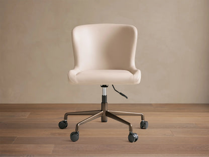 Kirsten Faux Leather Desk Chair, beige, angled slightly right on wood floor. Bronze powder-coated base with black casters.