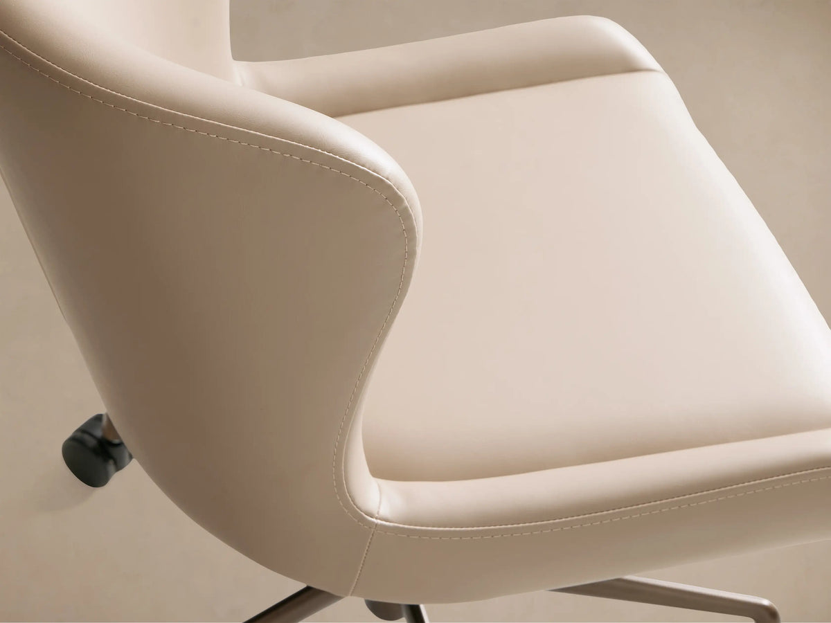 Kirsten Faux Leather Desk Chair, front view. Beige faux leather seat & back, bronze 5-star base with black casters on wood floor.