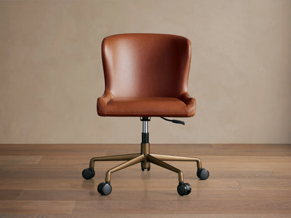 Kirsten Faux Leather Desk Chair in brown, featuring a curved backrest and seat. Swivel base on casters with bronze legs.