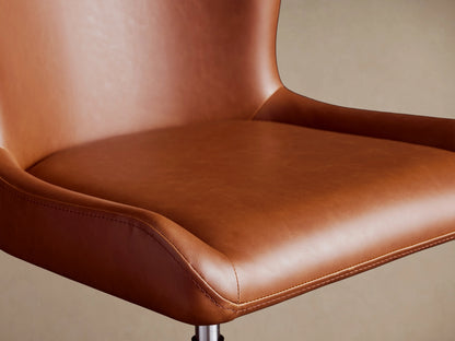Kirsten Faux Leather Desk Chair in brown, close-up of seat and backrest. Smooth faux leather with gentle curves and visible stitching.