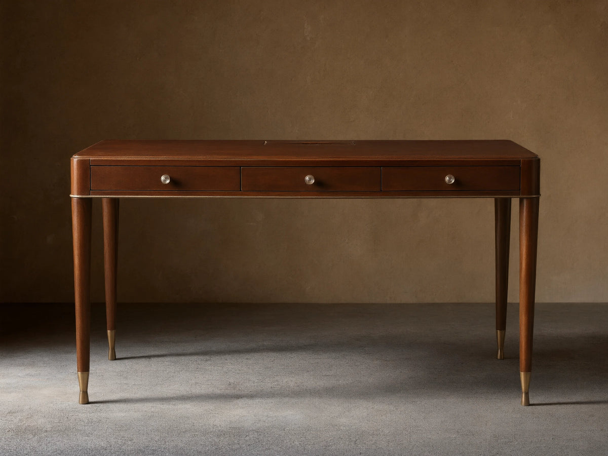 Front view of a dark brown wooden desk with three drawers, round silver knobs, and slim tapered legs with brass caps.