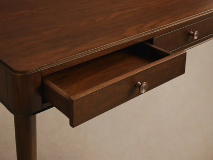 Close-up of a dark brown wooden desk with an open drawer, featuring a decorative brass-colored knob.