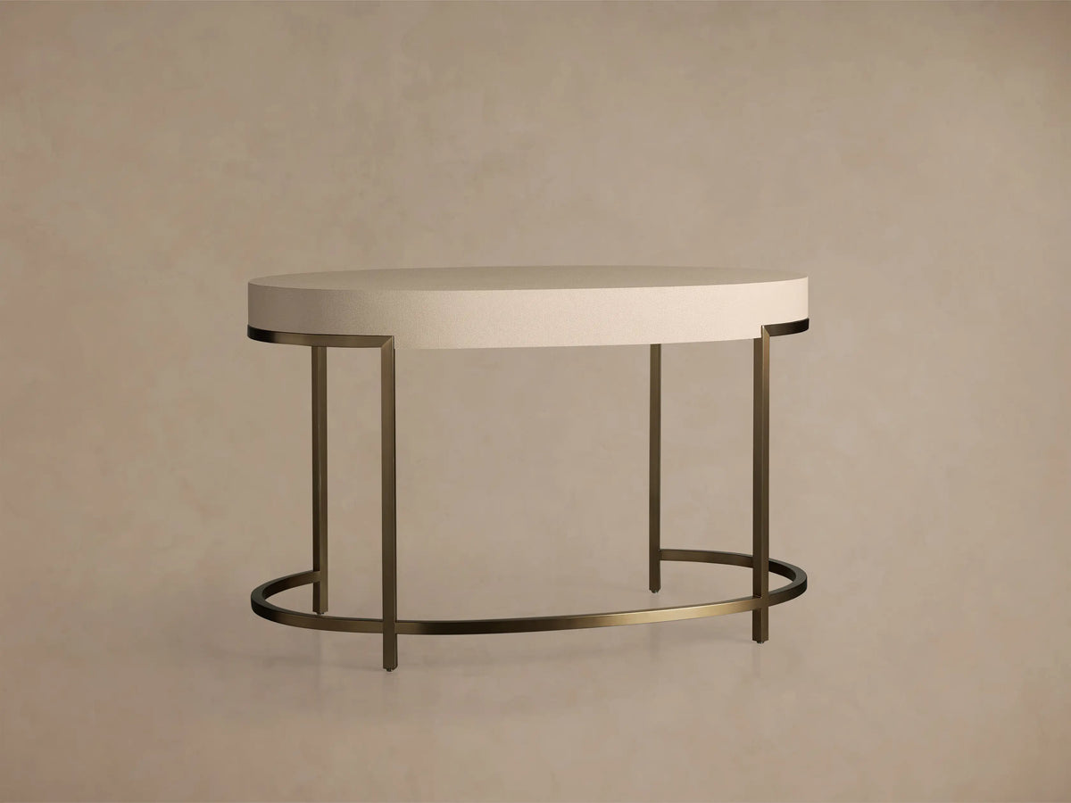 Front view of the Malone Writing Desk with an oval light beige reconstituted leather top and a warm brass steel base.
