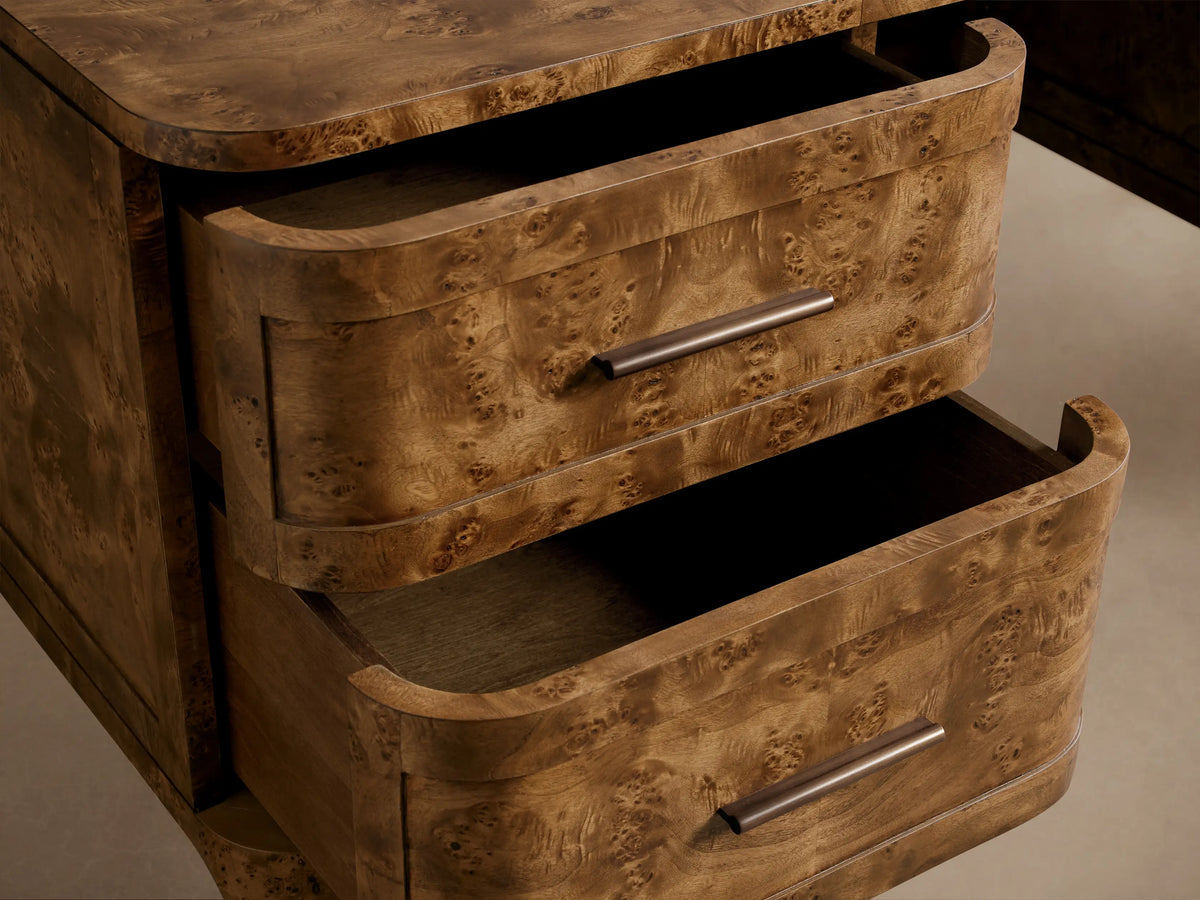 Close-up of the Mogadore Executive Desk, featuring two curved drawers partially open, crafted from mappa burl wood with antique brass handles.
