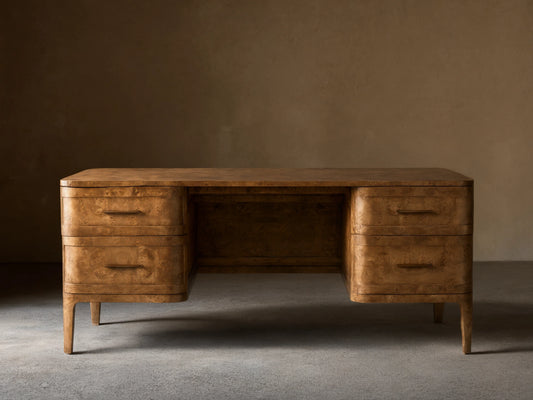Front view of the Mogadore Executive Desk, crafted from brown mappa burl wood with four drawers and antique brass handles.