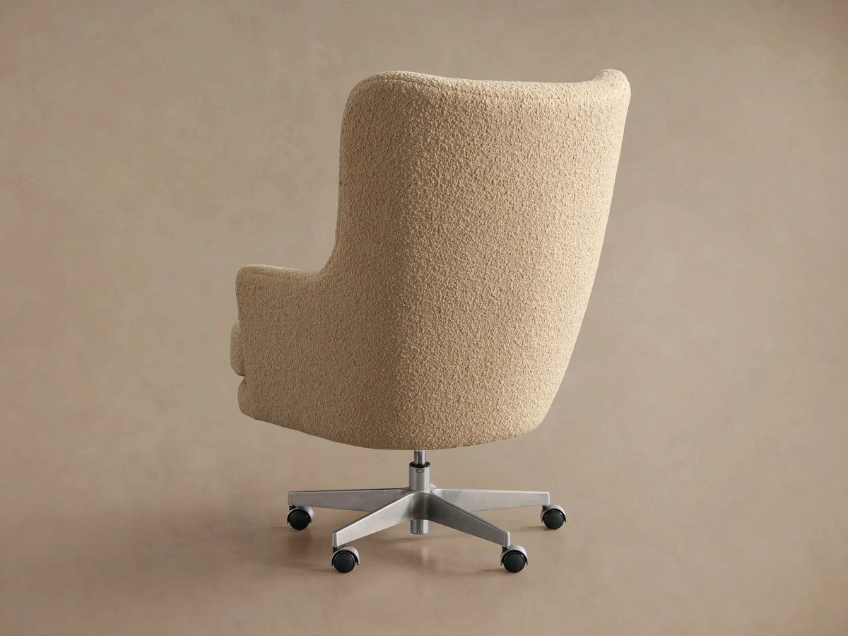 Angled close-up of Montrose Desk Chair, upholstered in textured cream boucle fabric, showing rounded arms & plush seat.