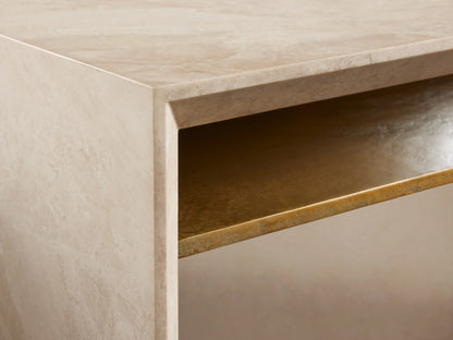 Sarsen Stone Desk with a smooth beige stone finish, rectangular top, and gold metal accent beneath. Set on a wooden floor.