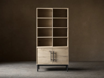 Sullivan Bookcase with Cabinet Base in light oak finish on hardwood floor, featuring upper shelves and lower cabinet with iron handles.