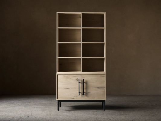 Sullivan Bookcase with Cabinet Base in light oak finish on hardwood floor, featuring upper shelves and lower cabinet with iron handles.
