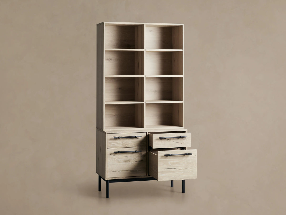 Sullivan Bookcase with File Base shown in light wood finish with four shelves above two drawer cabinets, black iron handles, on wooden floor.