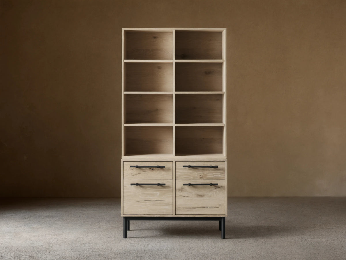 Sullivan Bookcase with File Base shown in light wood finish with four shelves above two drawer cabinets, black iron handles, on wooden floor.