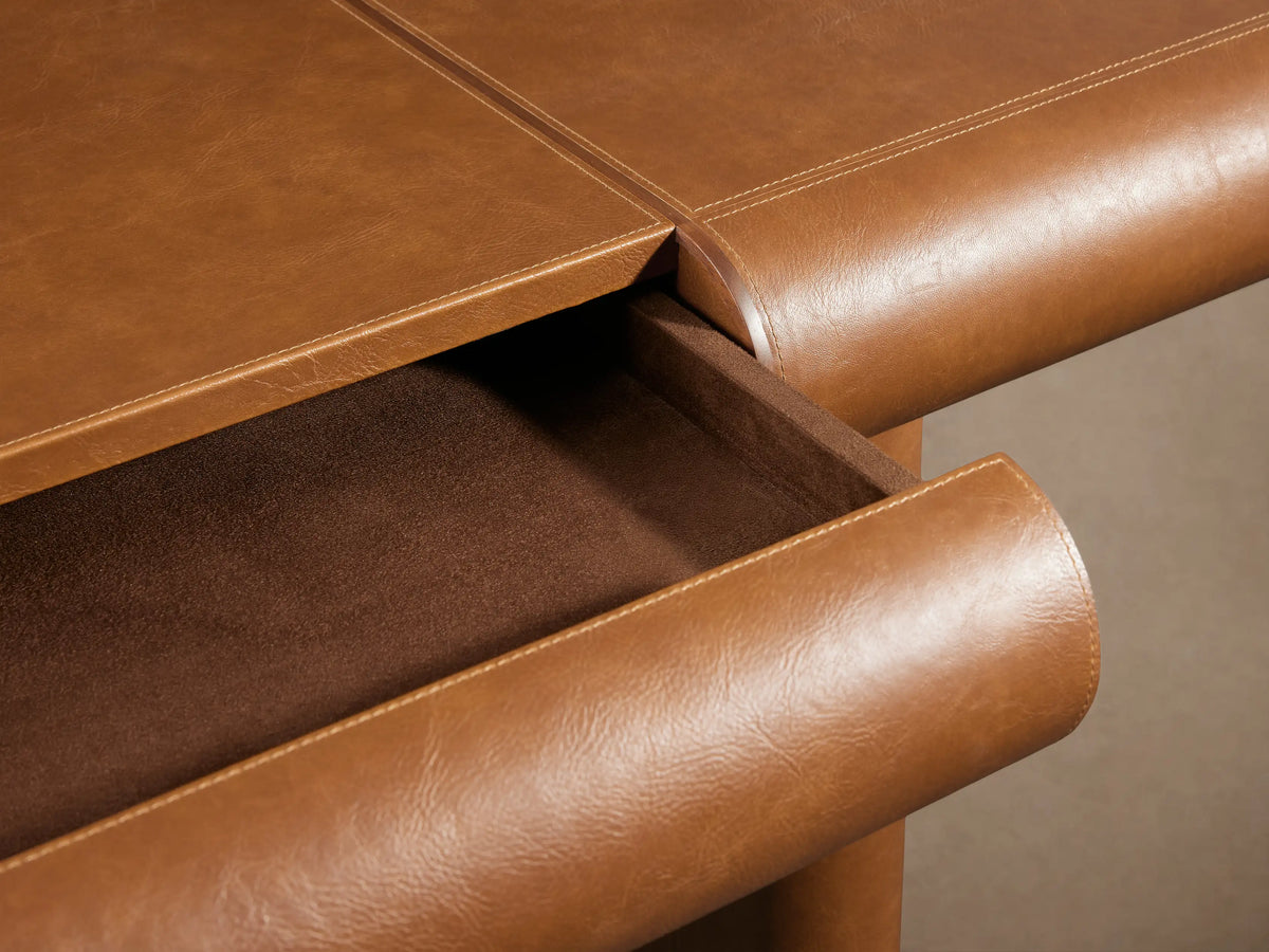 Tullson Leather Desk with engineered hardwood, faux leather, and walnut veneer accents. Features plinth legs with brass finish.