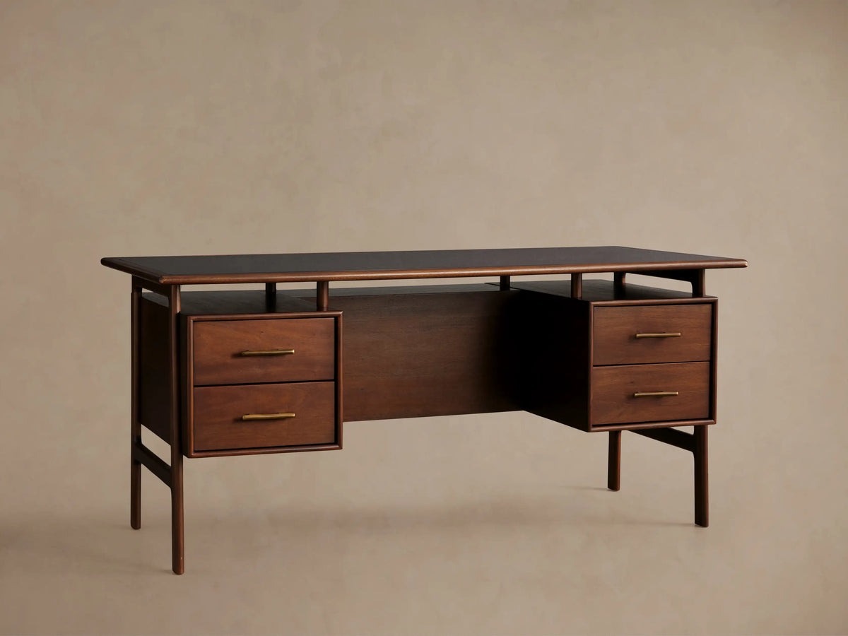 Dark, hand-stained mahogany Towry Executive Desk with a sleek black glass top, four drawers with brass pulls, and slender legs.