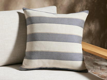 Dawson Outdoor Pillow, cream square with horizontal navy and tan woven stripes, upright against a beige textured wall.