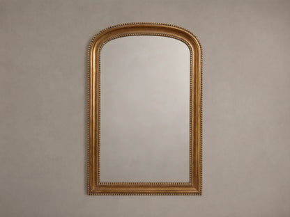 Pierre Bath Wall Mirror: arched-top, rectangular with a gold, beaded frame, hanging vertically on a neutral wall.