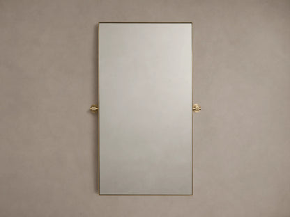 Monroe Bath Rectangular Wall Mirror in Brass with a slim brass frame, mounted against a beige wall with brass side accents.