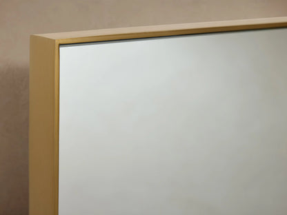 Monroe Bath Rectangular Wall Mirror in Brass with a slim brass frame, mounted against a beige wall with brass side accents.