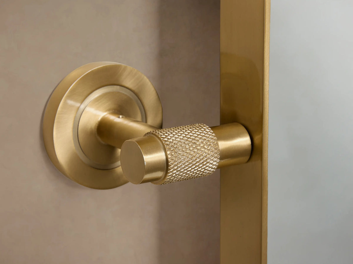 Rectangular wall mirror with a smooth brass frame, focused on the upper-left corner against a neutral background.
