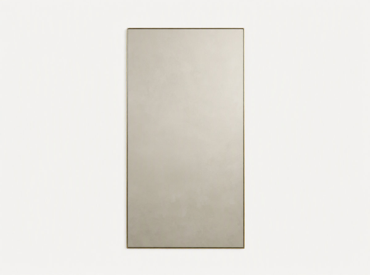 Lira Rectangular Bath Wall Mirror with a thin brass frame, hanging vertically against a neutral beige wall.