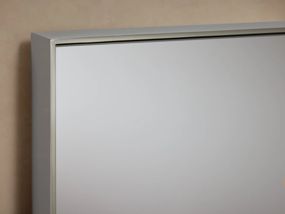 Lira Rectangular Bath Wall Mirror with a thin nickel frame, hanging vertically against a plain beige wall.