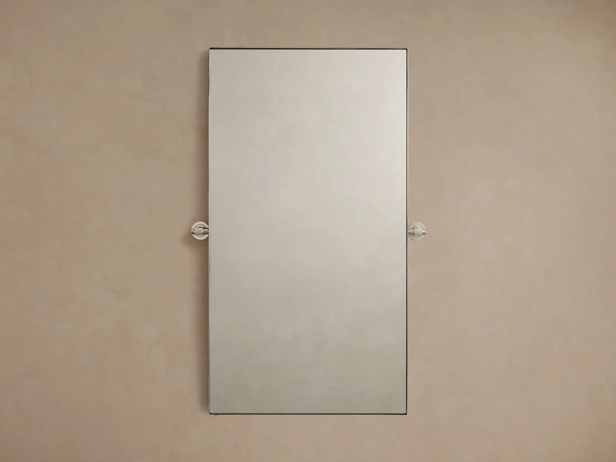 Monroe Rectangular Bath Wall Mirror with nickel finish, thin stainless steel frame, mounted on a beige wall with pivot hardware.