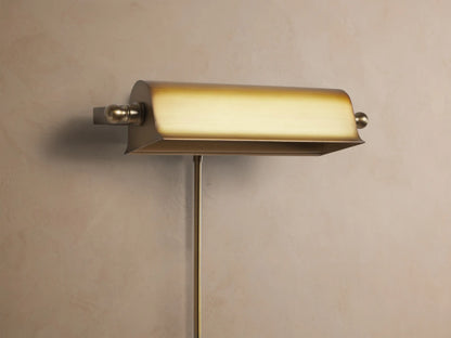 Tremont Picture Light Sconce with antiqued metallic gold finish mounted on a wall, casting a warm downward glow.