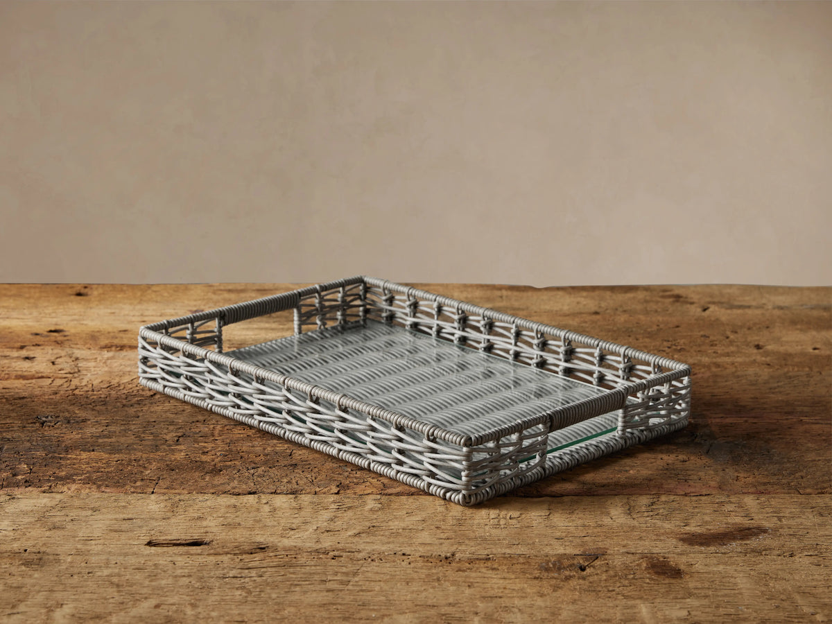 Rectangular Hatteras Serving Tray in grey/white woven material with glass insert, angled on a rustic wooden surface.