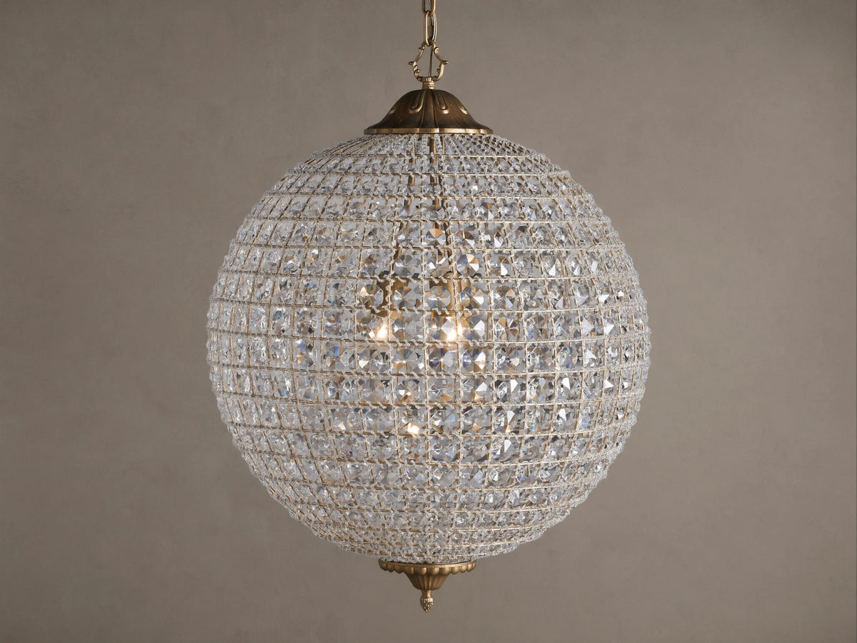 Poppy Chandelier, a glowing spherical fixture of clear multifaceted crystals on an antiqued brass frame, suspended.