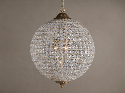 Poppy Chandelier, a glowing spherical fixture of clear multifaceted crystals on an antiqued brass frame, suspended.