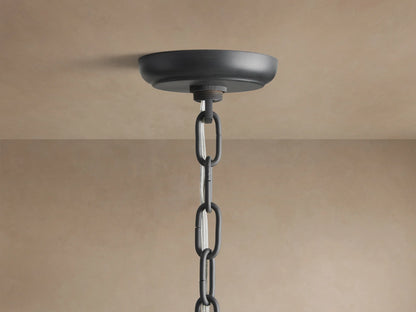 Leyland Chandelier with tiered black oil-rubbed frame, rows of clear, faceted K9 glass crystals, hanging against a plain wall.