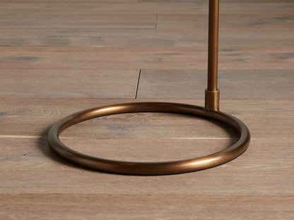 Kellen Antiqued Brass Floor Lamp. Side close-up of its antiqued brass arm & black tapered fabric shade with a warm interior.