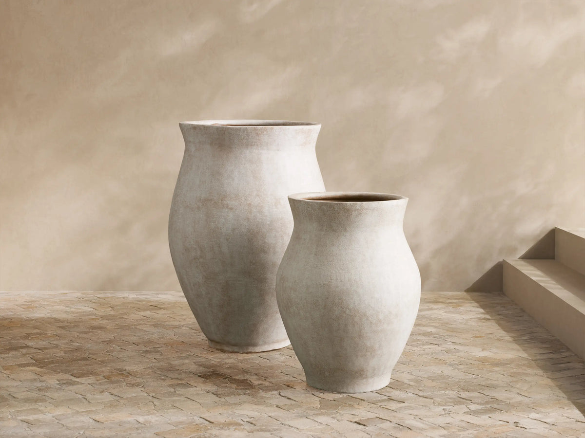 Gable Outdoor Planter: large, rounded, weathered grey aluminum pot with lush green foliage, on a stone patio.