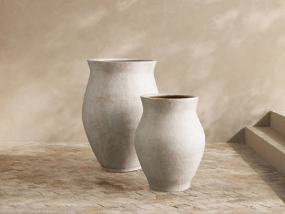 Gable Outdoor Planter: large, rounded, weathered grey aluminum pot with lush green foliage, on a stone patio.