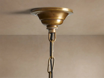 Close-up of Eliana Lantern Pendant: intricate gold brass geometric frame with clear glass panels, an E26 light bulb visible inside.
