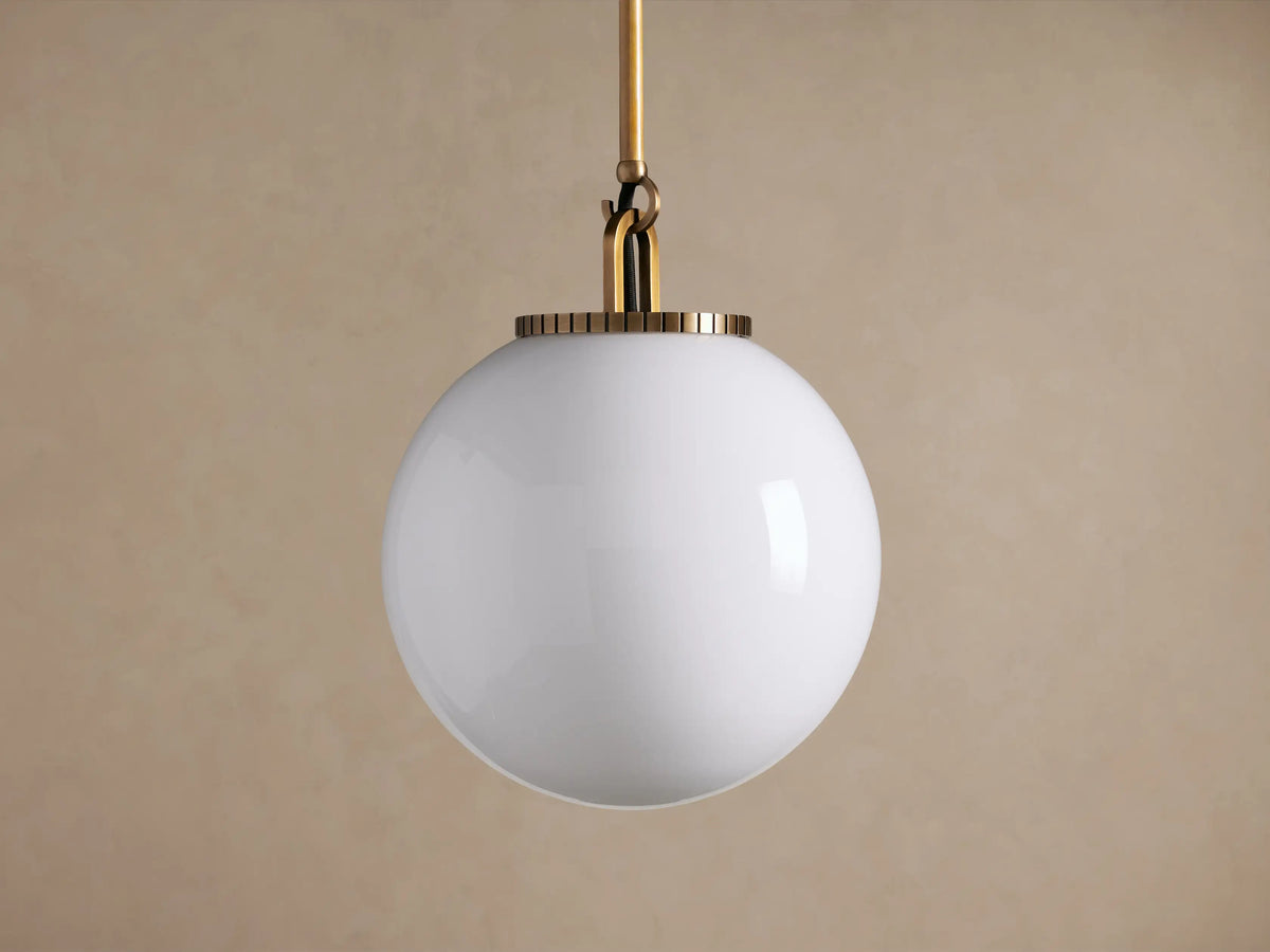 Wescott Globe Pendant with an illuminated white milk glass globe hanging from a brass rod against a neutral background.
