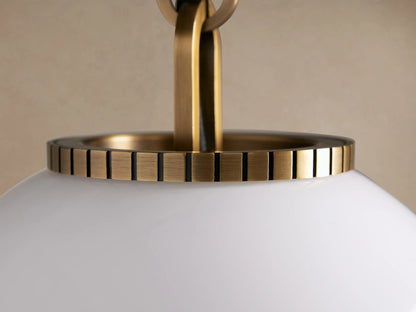 Wescott Globe Pendant. White milk glass globe with brass rod and fittings, hanging centered on a textured beige wall.