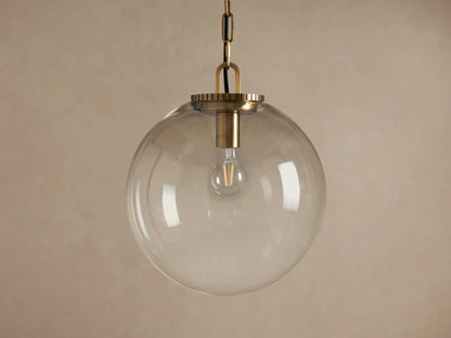 Wescott Globe Pendant with clear glass globe, brass finish chain, and visible bulb hanging against a neutral background.