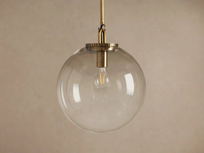 Wescott Globe Pendant: clear glass globe with a brass rod and exposed bulb, hanging against a warm, neutral wall.