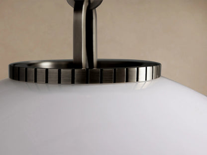 Wescott Globe Pendant with an opaque white milk glass globe, suspended by a dark bronze rod & cap, against a neutral wall.