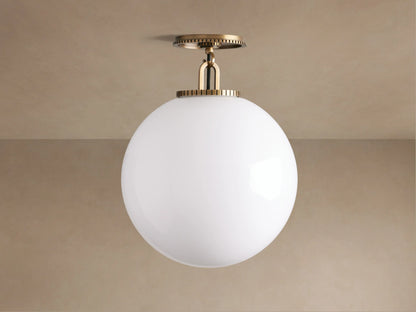Wescott Globe Flush Mount: large white milk glass globe with ribbed brass hardware, mounted on a light tan ceiling.