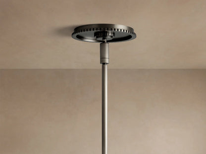 Wescott Globe Pendant close-up: dark bronze rod and ribbed cap connect to a clear glass globe, hanging against a wall.