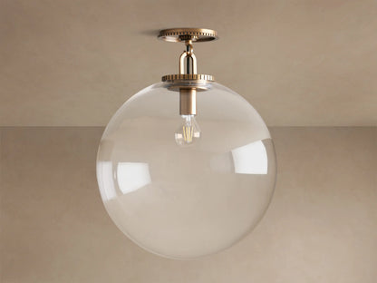 Wescott Globe Flush Mount with clear glass globe, exposed Edison bulb, and brass hardware, mounted on a beige ceiling.