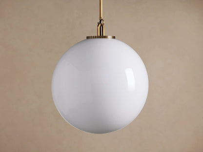 Wescott Globe Pendant: White milk glass sphere suspended from a thin brass rod, centered on a simple beige background.