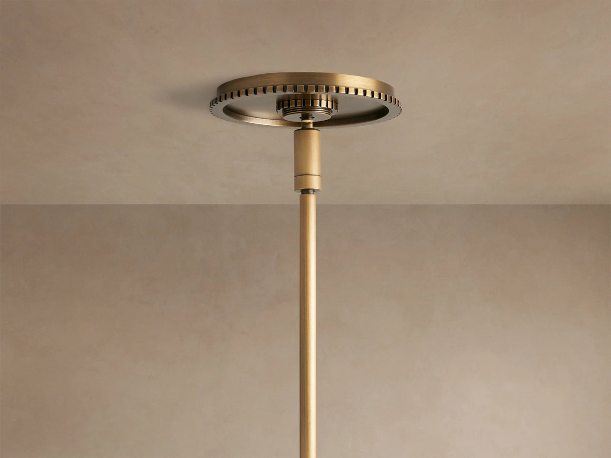 Close-up of Wescott Globe Pendant, milky white glass globe connected to a brushed brass metal band with vertical grooves and rod.