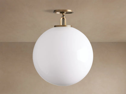 Wescott Globe Flush Mount, large white milk glass globe light with brass ribbed canopy, mounted on a ceiling.
