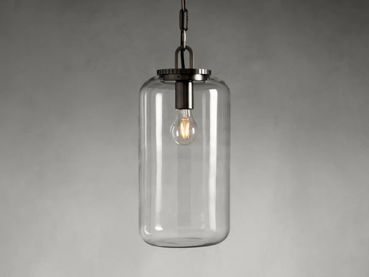 The Wescott Cylinder Pendant features a clear glass cylinder shade with visible filament bulb and brass or bronze fittings, suspended by a chain.