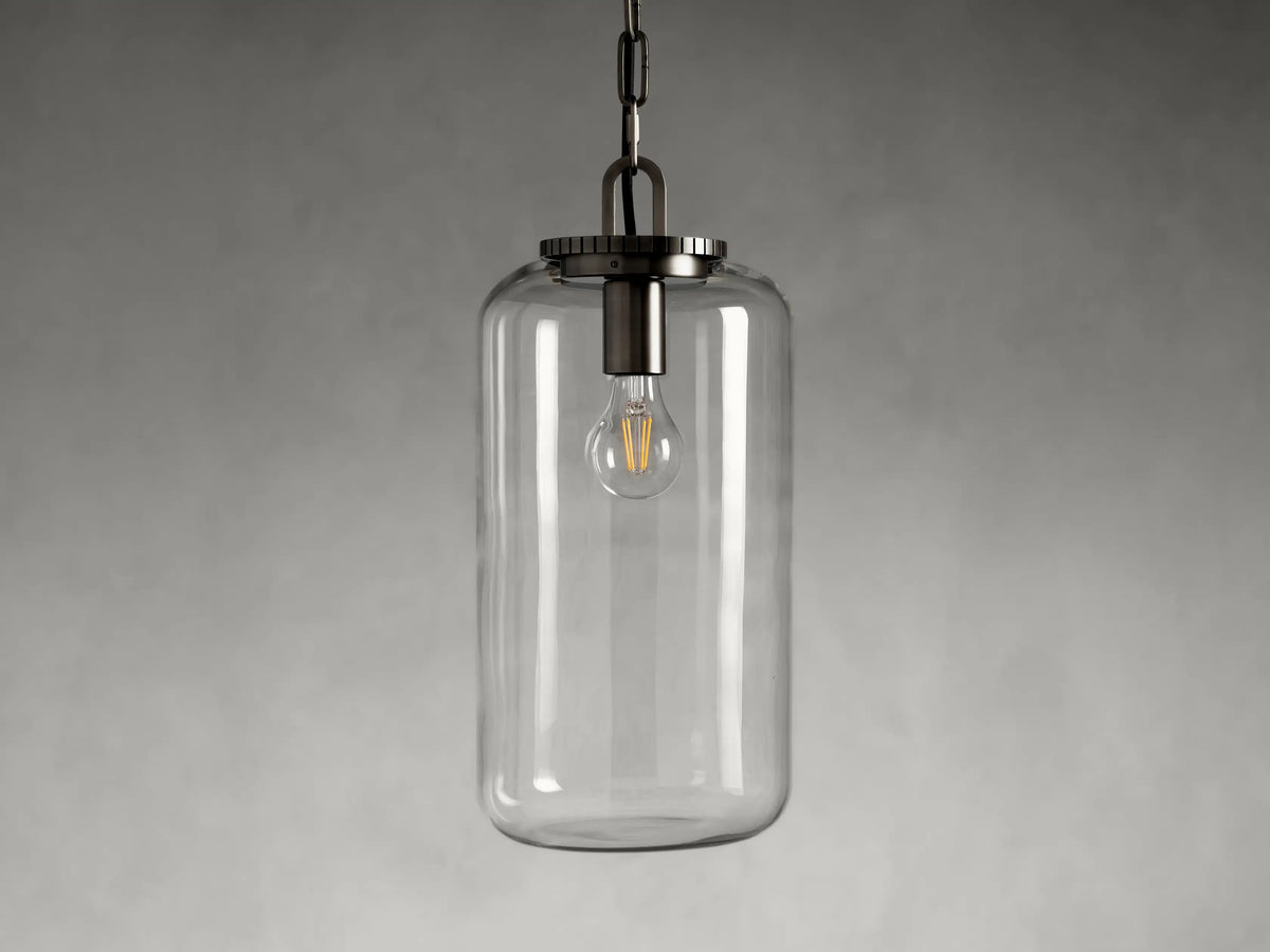 Wescott Cylinder Pendant with a clear glass shade hanging from a chain. Visible interior bulb, steel fixture in dark finish.