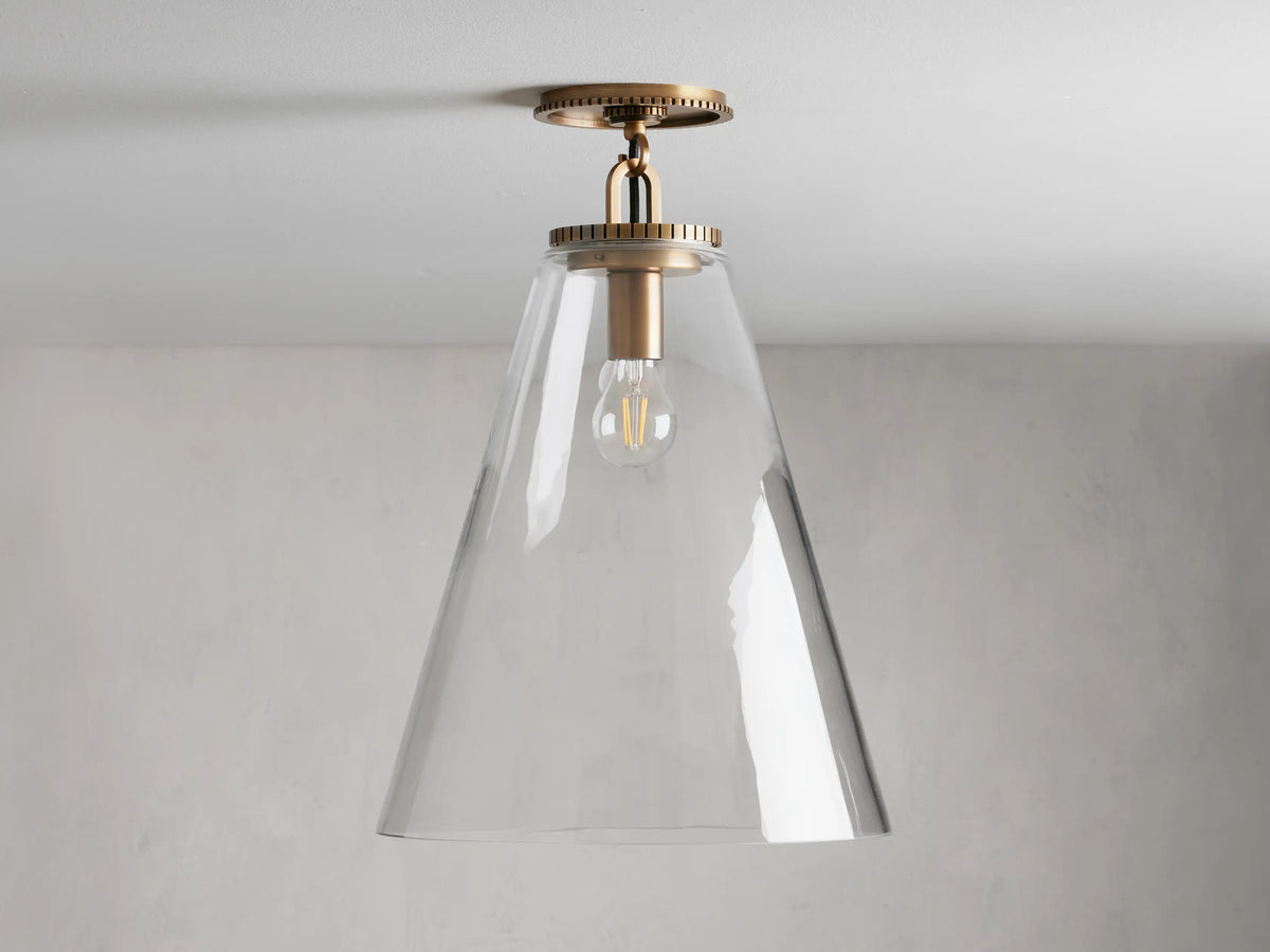 Wescott Cone Flush Mount with brass finish and clear glass cone shade, mounted on ceiling. Bulb visible inside.