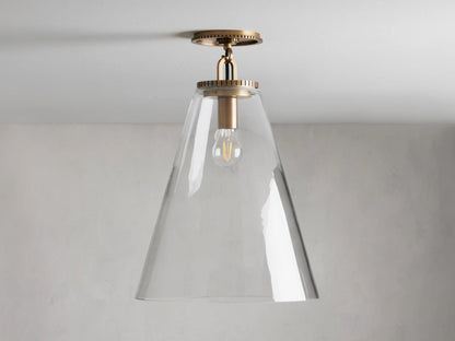 Wescott Cone Flush Mount with brass finish and clear glass cone shade, mounted on ceiling. Bulb visible inside.