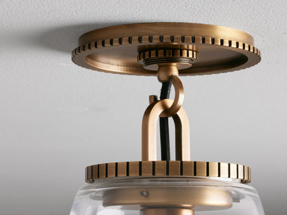 Clear glass cone shade flush mount light with brass finished base, mounted on the ceiling. Bulb visible inside.
